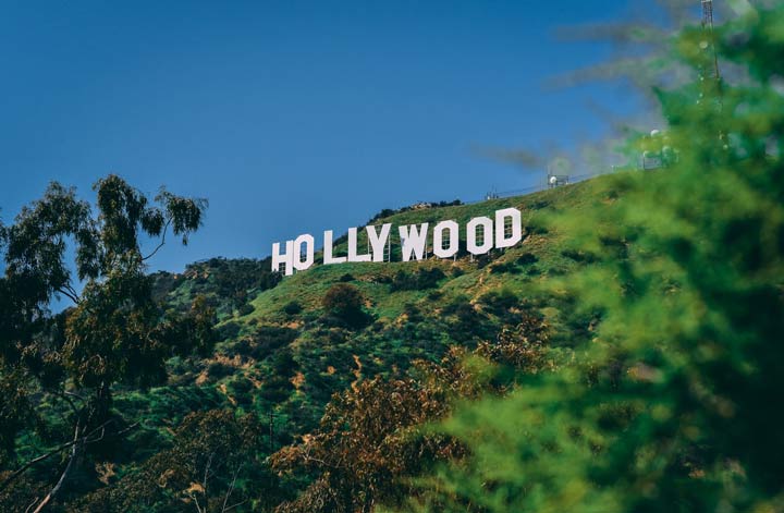 the Hollywood sign on a day with clear blue skies and bright green trees on the hills