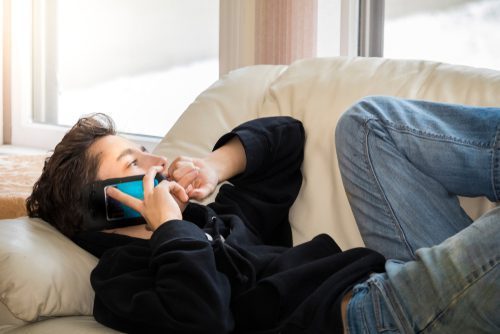 man on phone laying on couch