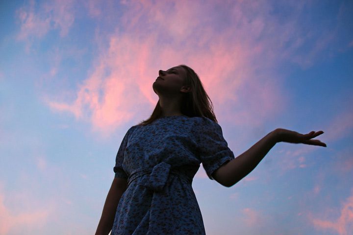 woman in a dress outside with pink clouds in the sky - pink cloud syndrome